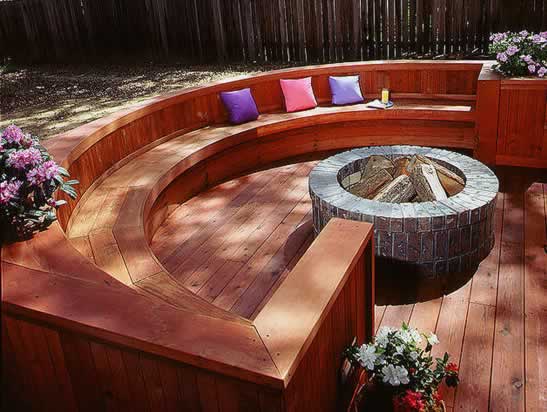 Curved redwood bench arcs around a stone firepit.