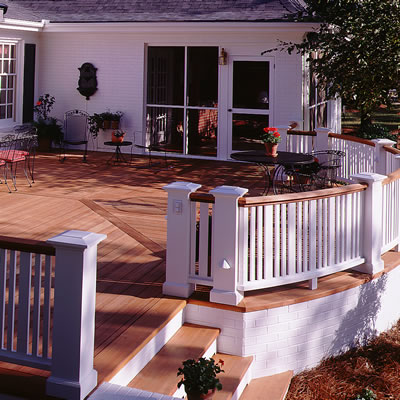 A spacious redwood deck includes a curved balustrade. The top rail of the balustrade is natural redwood, the newels and balusters are painted white. 